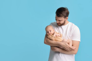 Açık mavi arka planda sevimli bebeği olan baba, mesaj için boşluk.