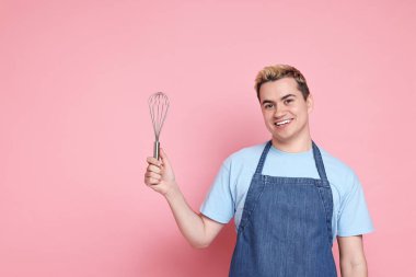 Pembe arka planda çırpıcı tutan mutlu şekerci portresi, metin için boşluk