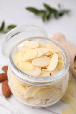 Kavanozda taze badem gevreği ve beyaz desenli masada fındıklar, yakın plan.