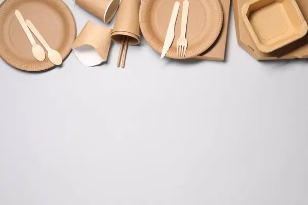 Eco friendly food packaging. Paper containers and tableware on light grey background, flat lay. Space for text