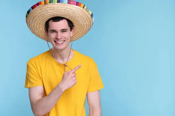 Молодой Человек Мексиканской Шляпе Сомбреро Указывает Светло Голубом Фоне Пространство — стоковое фото