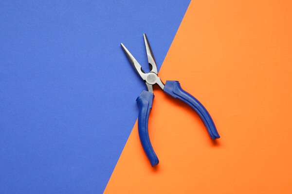 Needle nose pliers on color background, top view
