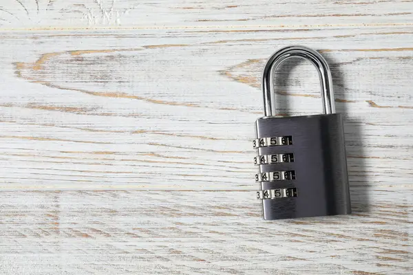 One steel combination padlock on white wooden table, top view. Space for text