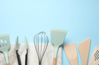 Farklı spatulalar, açık mavi arka planda çırpma ve maşa, düz yatış. Metin için boşluk