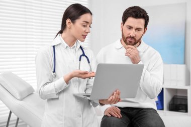 Klinikteki randevusu sırasında laptopta danışmanlık yapan bir doktor.
