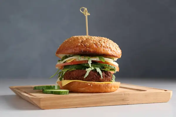 Board with delicious vegetarian burger on white table