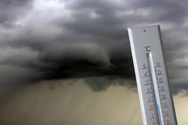 Autumn or spring weather. Thermometer against thundercloud