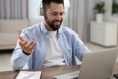 Kulaklıklı genç adam masadaki Webinar sırasında görüntülü konuşma yapıyor.