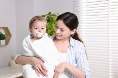 Anne evde banyo yaptıktan sonra küçük bebeğini havluyla sarıyordu.