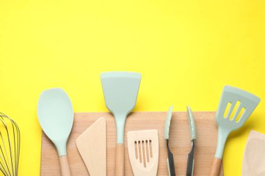 Sarı arka planda farklı spatula ve maşalar var. Metin için boşluk