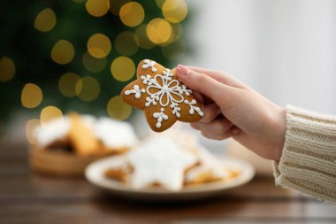 Masada süslü Noel kurabiyesi olan kadın, yakın plan.