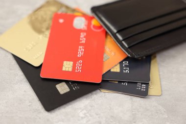 Gri masada bir sürü farklı kredi kartı ve deri cüzdan var.