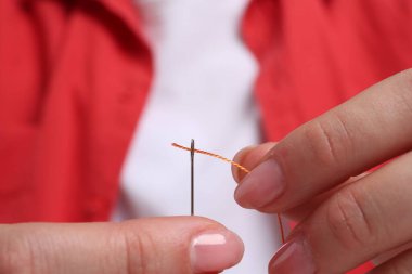 Kadın iğne deliğinden iplik sokuyor, yakın plan.