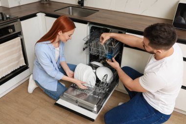 Güzel bir çift bulaşık makinesini tabakla dolduruyor.
