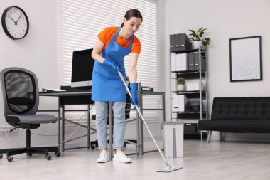Temizlik servisi. Ofiste yerleri paspasla silen bir kadın.