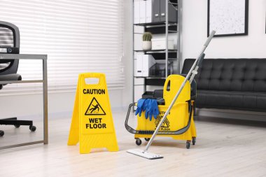 Temizlik servisi. Paspas, ıslak tabela ve ofiste malzeme dolu kova.