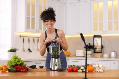 Mutfakta video kaydederken gülümseyen yemek blogcusu yemek pişiriyor