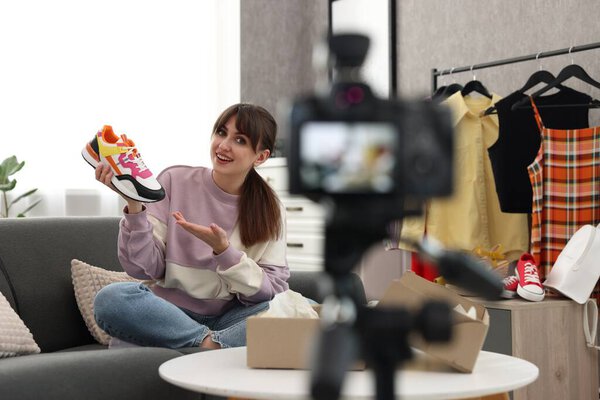 Smiling fashion blogger showing her shoes while recording video at home