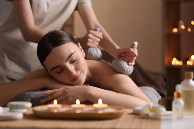 Spa terapisi. Güzeller güzeli genç bir kadın, kuaförde bitkisel masaj sırasında masada yatıyor.