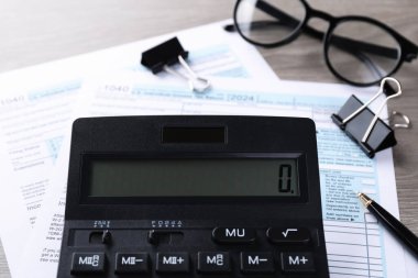 Vergi muhasebesi. Hesap makinesi, belgeler, bardaklar ve kırtasiye malzemesi ahşap masa, yakın plan