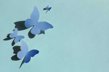 Cyan arka planda parlak mavi kağıt kelebekleri