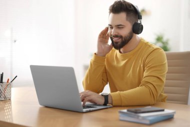 Kulaklıklı genç adam masadaki Webinar 'ı izliyor.