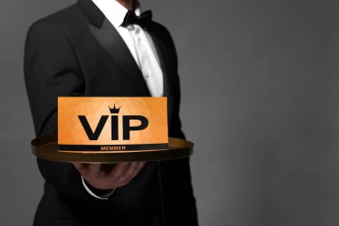 Man holding tray with VIP sign on grey background, closeup. Space for text clipart