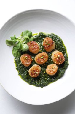 Lezzetli soslu leziz kızarmış deniz tarakları ve beyaz arka planda mısır salatası.