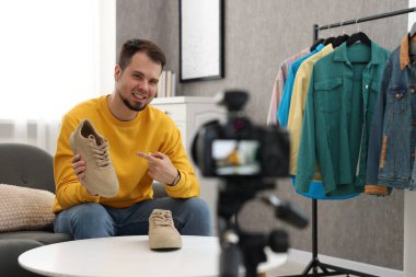 Gülümseyen moda blogcusu evde video kaydederken ayakkabılarını gösteriyor