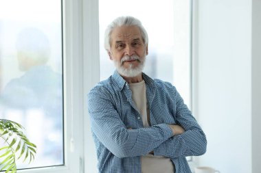Pencerenin yanında gri saçlı mutlu büyükbabanın portresi.