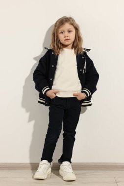 Moda konsepti. Beyaz duvarın yanında poz veren şık kız.