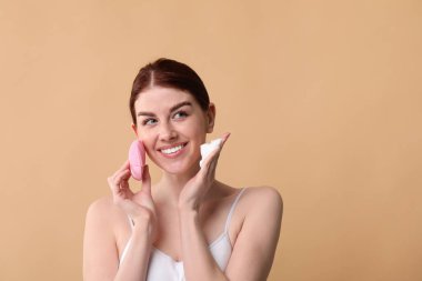 Yüzünü yıka. Bej arka planda fırça ve temizlik köpüğü olan genç bir kadın, mesaj için boşluk