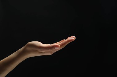 Siyah arka planda elinde bir şey tutan bir kadın, yakın plan. Metin için boşluk