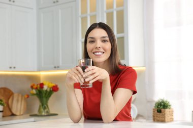 Mutfakta bir bardak suyu olan genç bir kadın.