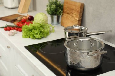 Yemek pişiriyorum. Mutfaktaki tezgahta tencere, tencere ve taze sebzeler.