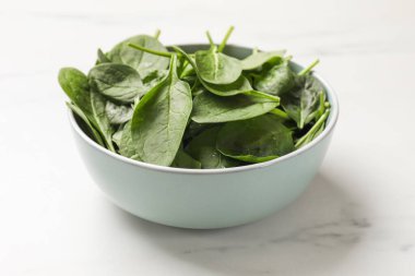 Beyaz mermer masada taze ıspanak yaprakları, yakın plan.