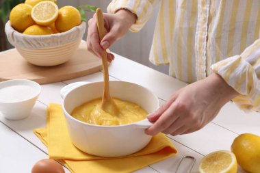 Beyaz ahşap masada limon kaymağı pişiren kadın, yakın plan.