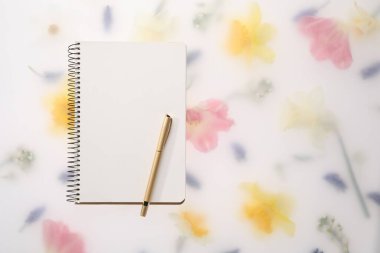 Konuk listesi. Bahar çiçekli arka planda defter ve kalem düz yatıyordu. Metin için boşluk