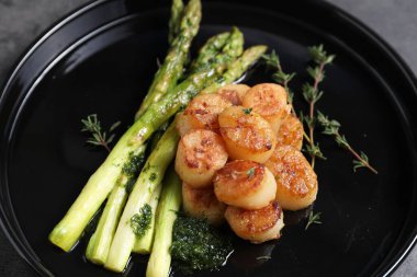 Gri masada kuşkonmaz ve kekik ile lezzetli kızarmış midyeler, yakın plan.