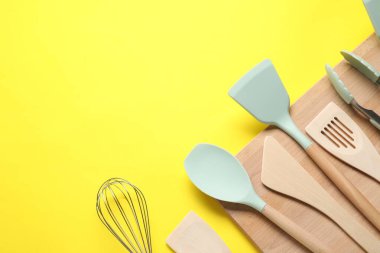 Farklı spatulalar, sarı arka planda çırpma ve maşa, düz yatış. Metin için boşluk