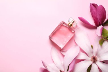 Güzel manolya çiçekleri ve pembe arka planda bir şişe parfüm. Metin için boşluk