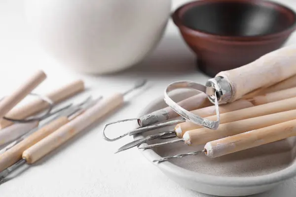 Set of different clay crafting tools on white table, closeup