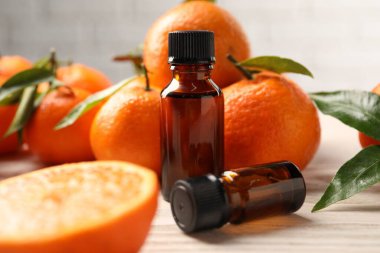 Mandalina yağı şişeleri ve ahşap masada taze meyveler, yakın plan.