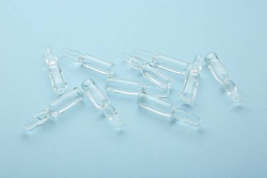 Açık mavi zemin üzerinde sıvı bulunan cam ampuller