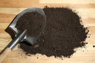 Tahta yüzeyde metal kürek ve toprak, üst manzara.