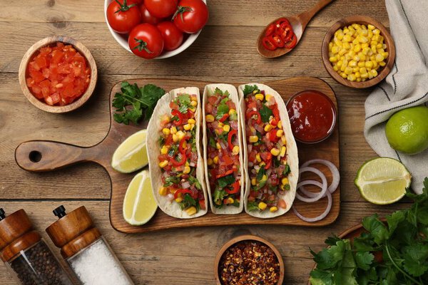 Tasty tacos with vegetables on wooden table, flat lay
