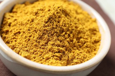 Curry powder in bowl on table, closeup clipart