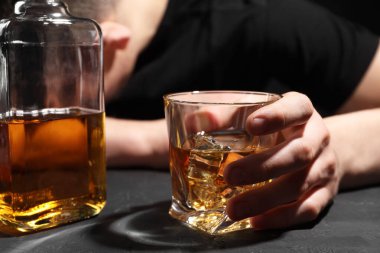 Alkol bağımlılığı. Koyu dokulu masada viskisi olan adam, seçici odaklı.