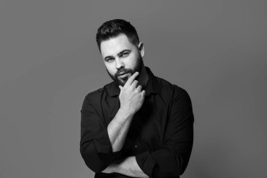 Gri arka planda sakallı yakışıklı bir adamın portresi. Siyah ve beyaz etkisi