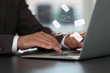 E-posta. Masada dizüstü bilgisayar kullanan adam, yakın plan. Aygıt üzerine harf çizimleri